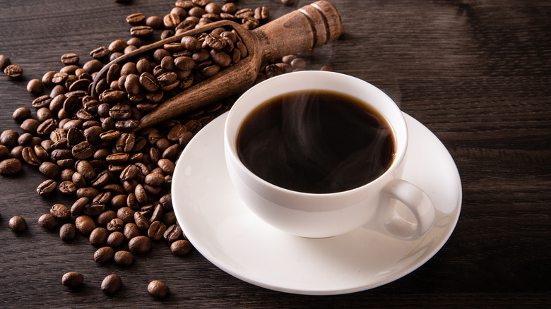 Black coffee in whit mug with coffee beans