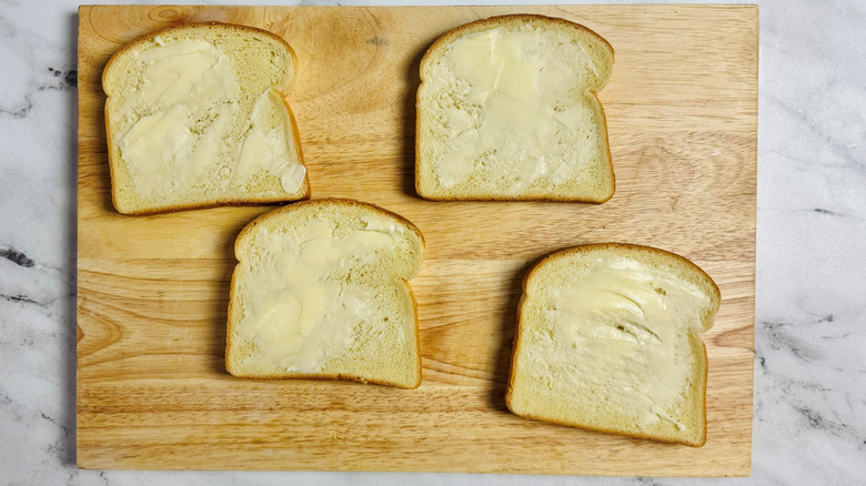 sliced white bread with butter on a wooden board