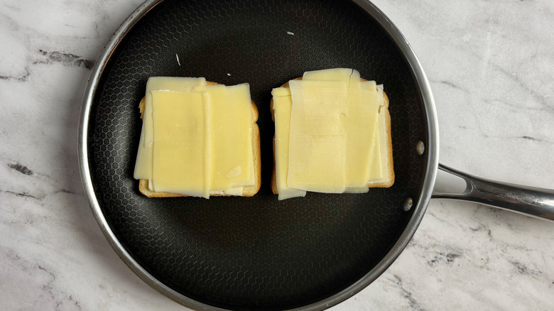 bread covered with sliced cheese in a frying pan