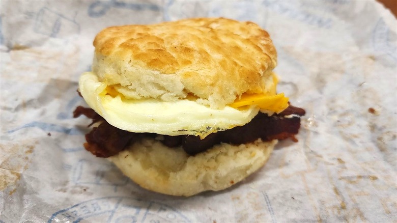 A fast food breakfast biscuit sandwich with bacon, egg, and cheese.