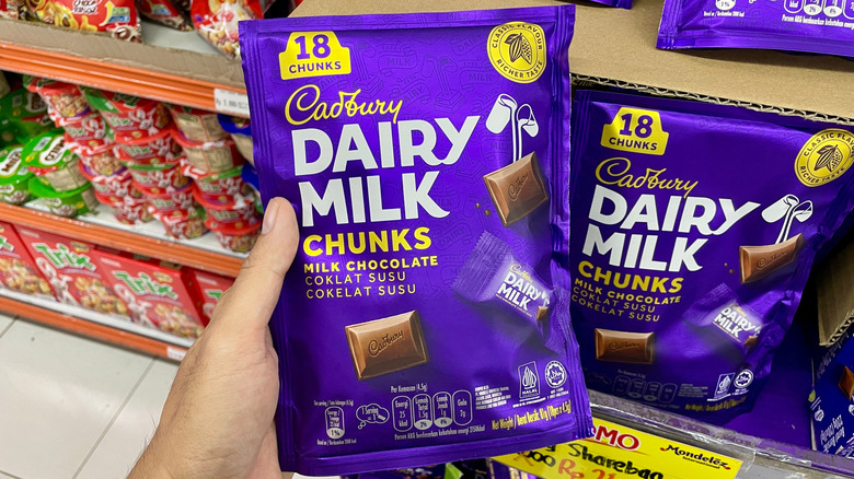 person holding bag of Cadbury chocolate in grocery store