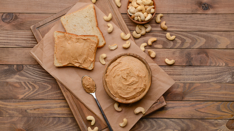 Cashew butter on a wooden table with sliced bread