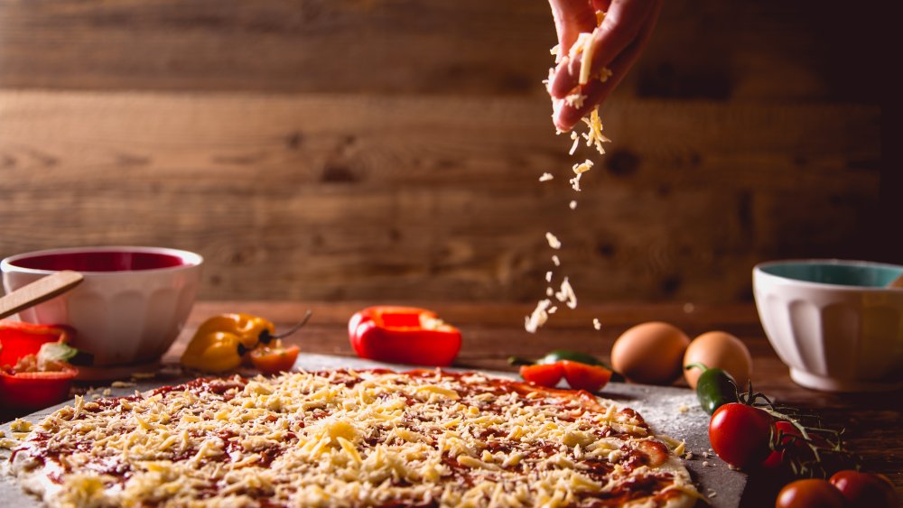 parmesan cheese being sprinkled over pizza 