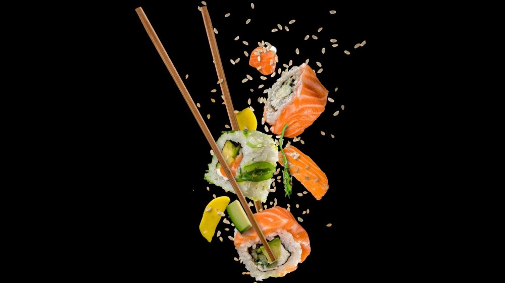 sushi in the air with chopsticks and sesame seeds 