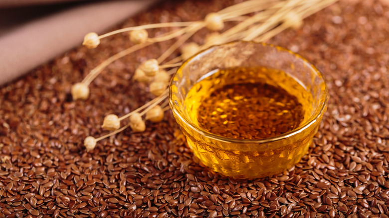 Small bowl of flaxseed oil with seeds and plant