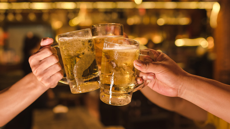 People clinking three mugs of beer