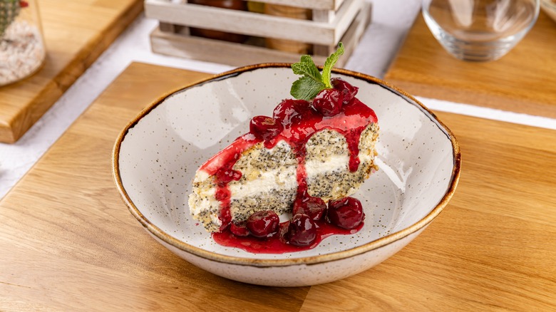 Slice of layered poppy seed cake with cherry topping