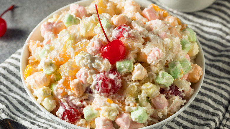 Bowl of Ambrosia Salad with mini marshmallows and a maraschino cherry on top
