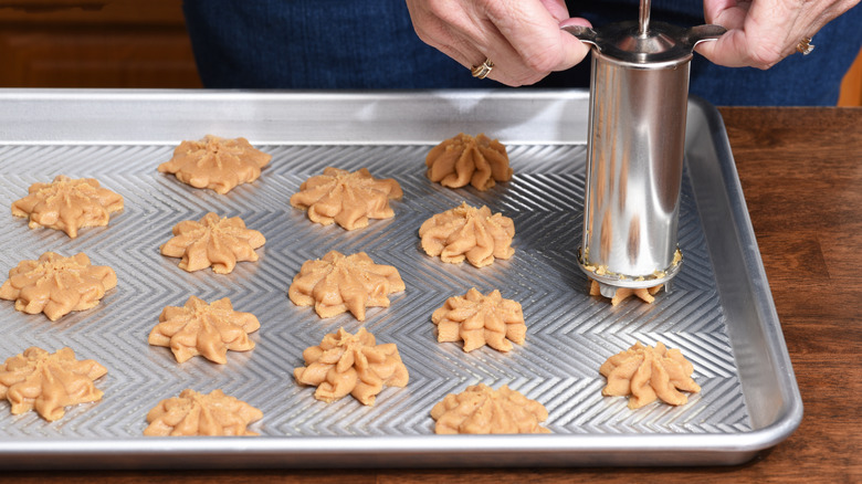 home baker using a cookie press to form cookies