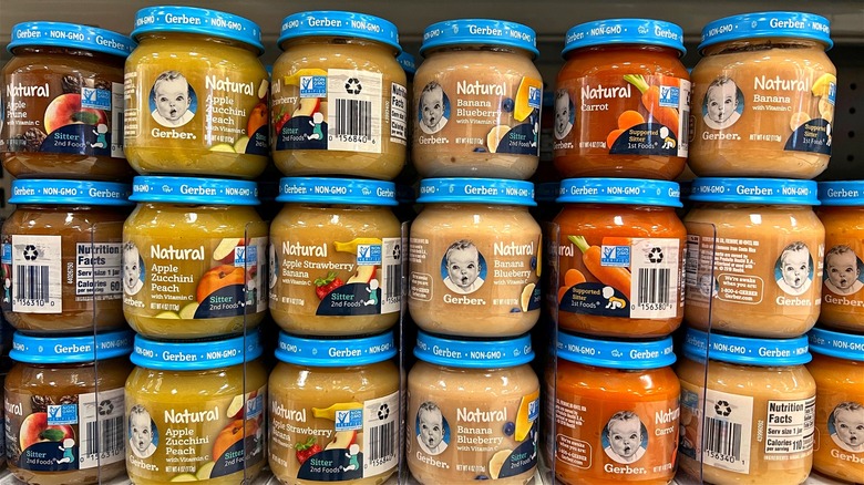 Jars of assorted Gerber baby food products on a grocery shelf.