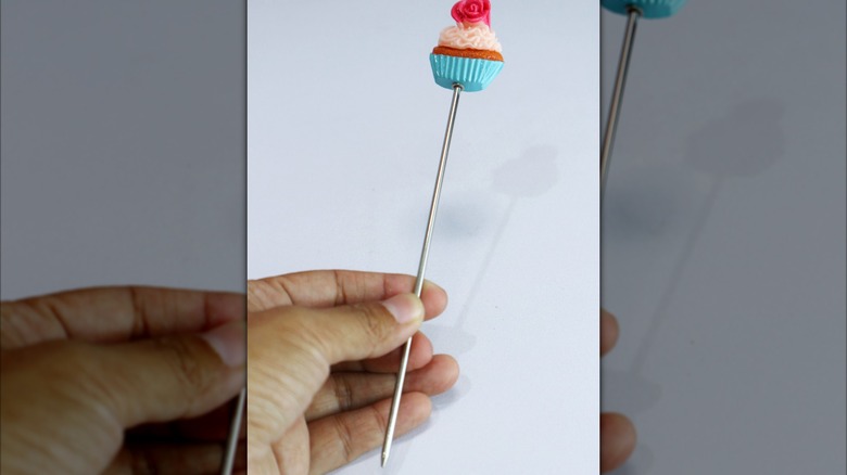 Long metal cake tester with cupcake on top