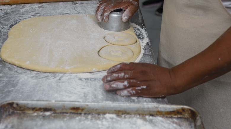 Person using donut cutter to make donuts