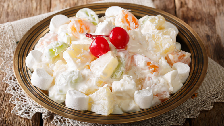 A bowl filled with ambrosia salad topped with two cherries