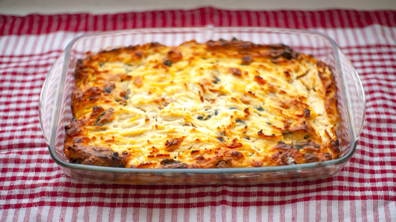 Cheese pudding in a glass baking dish on a red and white checkered tablecloth