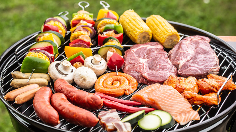 A barbecue grill filled with an assortment of meats, skewers, and vegetables