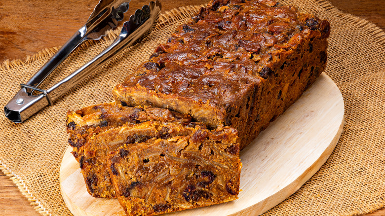 fruitcake loaf on board with tongs