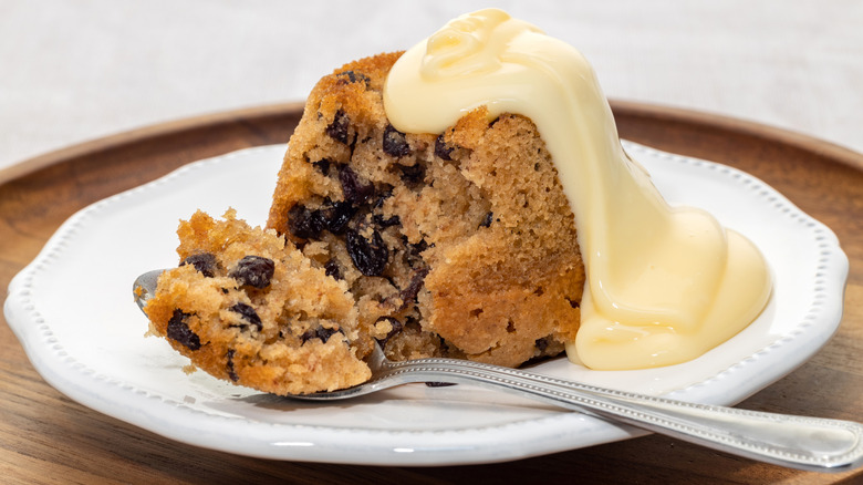 spotted dick with custard on white plate with spoon