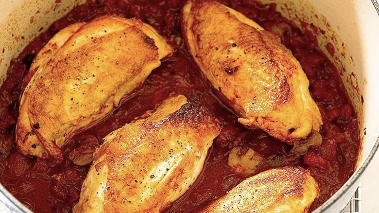 Chicken pieces in a pot of tomato sauce