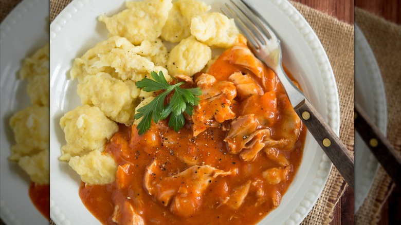 Red sauced chicken with herb garnish and spaetzle