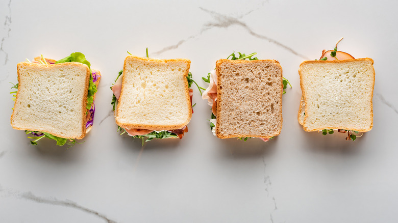 Four sandwiches on white marble.