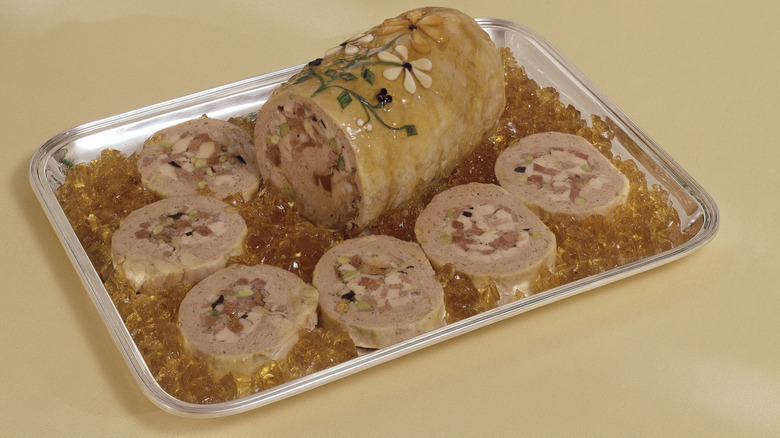 Chicken gelatin loaf on metal tray with flower garnish.