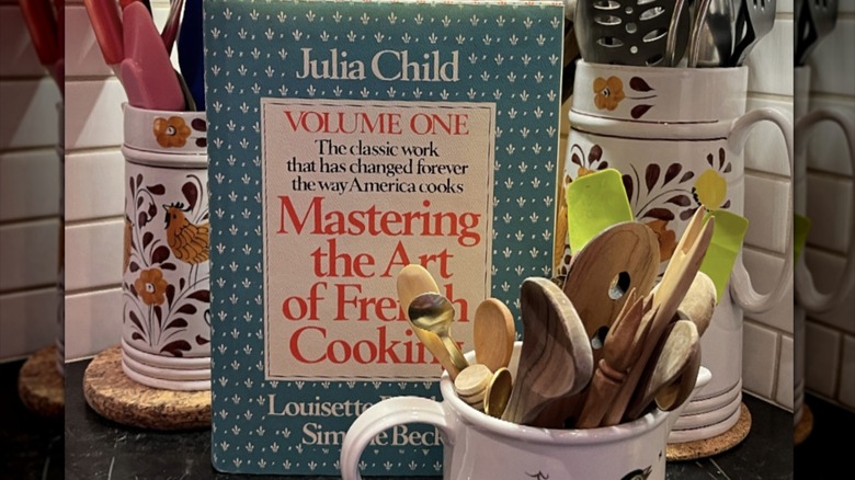 Julia Child cookbook with assorted cooking utensils on the side