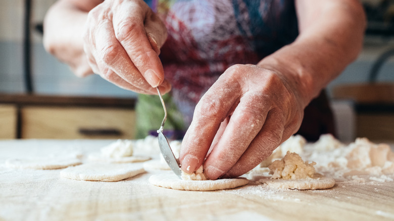 A close-up of a grandmother's hands putting filling in dough