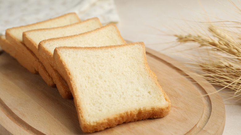 Multiple slices of white bread on a wooden cutting board