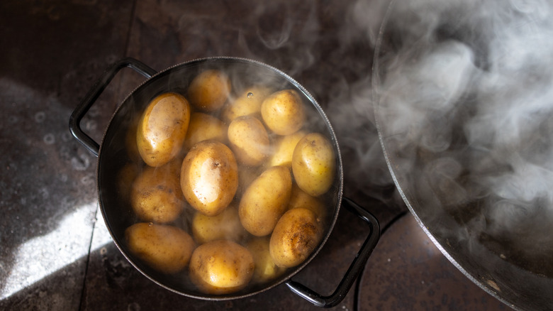 A close-up of a pot filled with boiled potatoes in steaming water