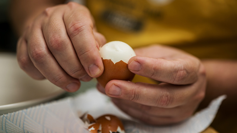A hand removing the shell of a boiled egg