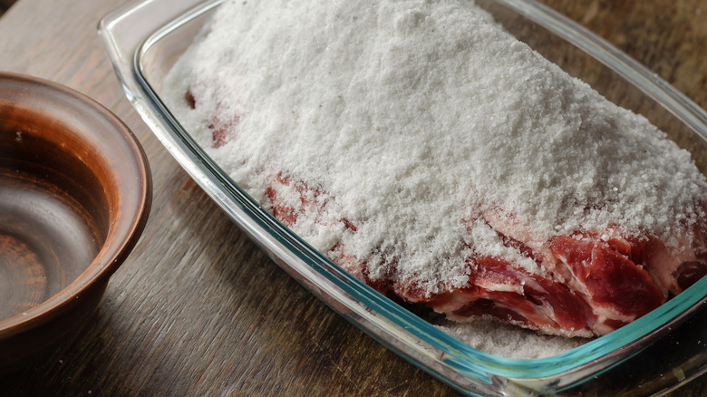 Dry brining meat with salt in a glass dish