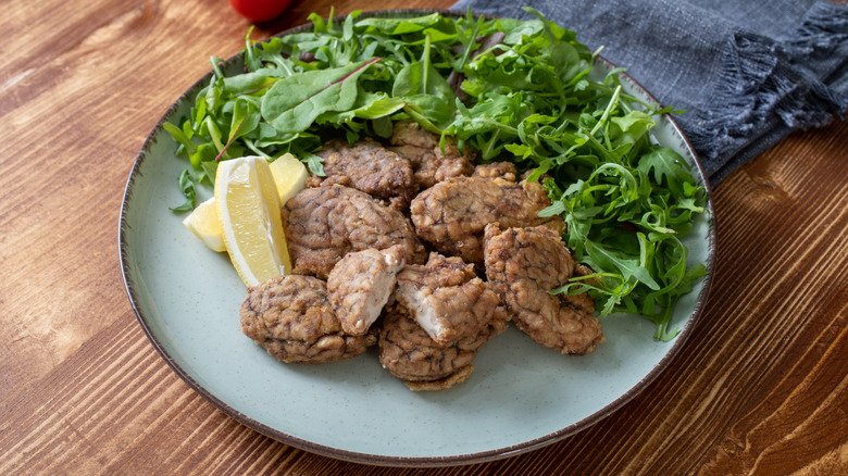 fried pork brains on plate with lemon garnish and salad
