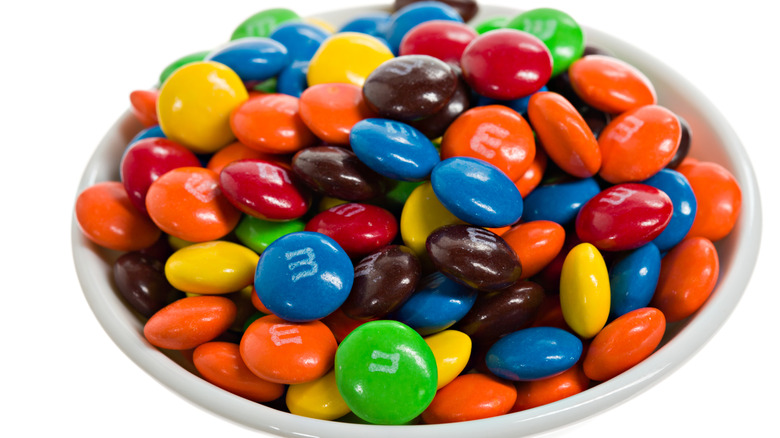 a white bowl full of multicolored M&Ms