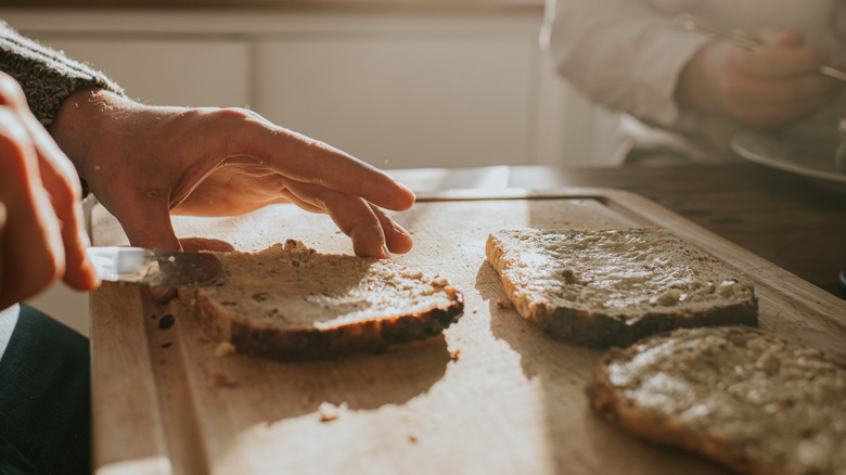 person speading butter on a piece of toast
