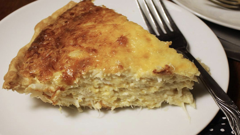Slice of crab pie on white plate with fork