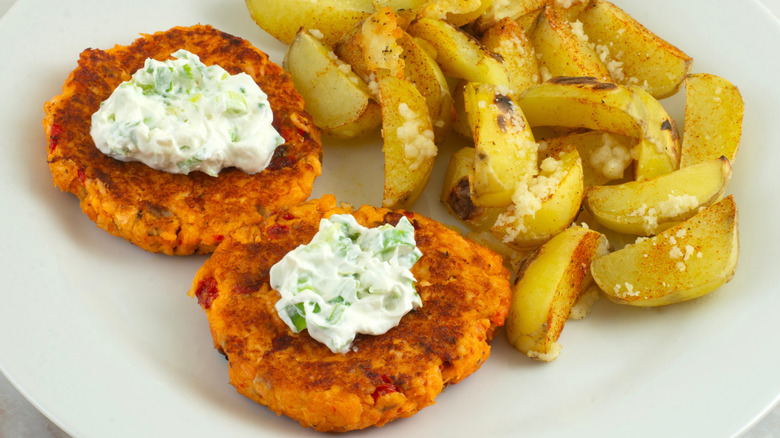 Salmon patties with dollops of white herbed sauce and potatoes