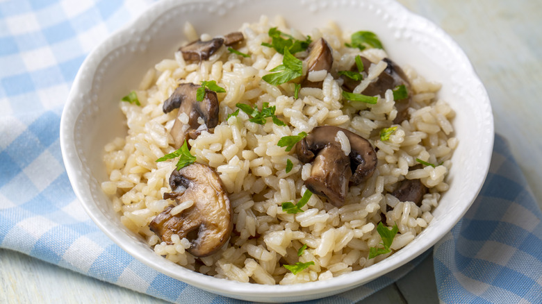 A bowl of rice and mushrooms topped with chopped herbs