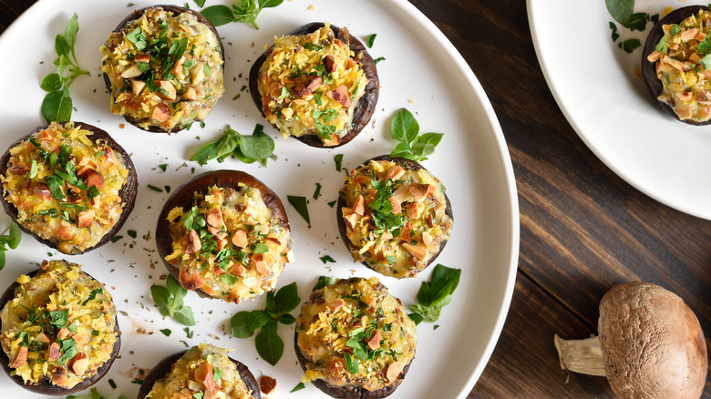A plate of 8 stuffed mushrooms garnished with fresh herbs