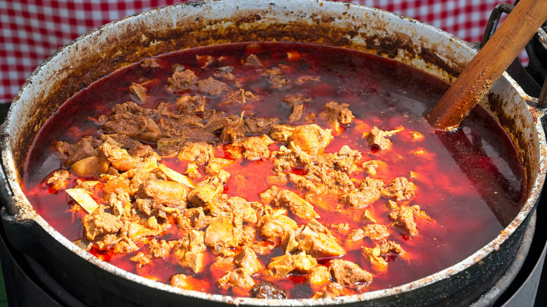 Mutton stew in large pot with red broth