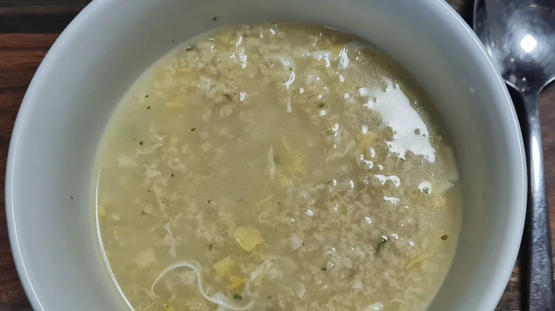 Bowl of oatmeal soup with spoon on wooden table