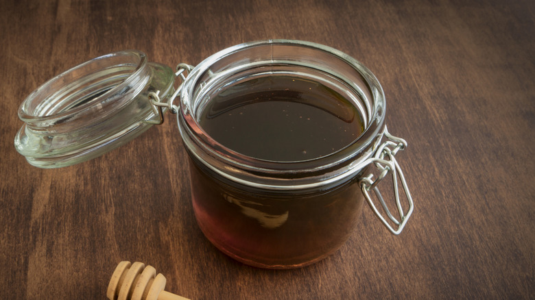 Glass jar of syrup on a wood table