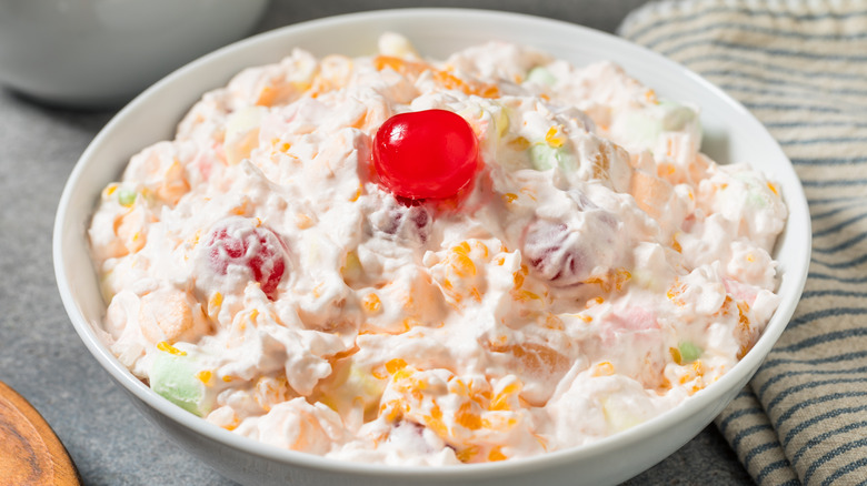 Ambrosia made of fruit and whipped cream in a white bowl.