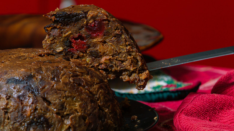 A serving knife pulls a slice of figgy pudding.