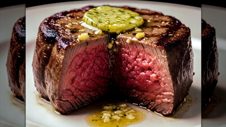 A seared filet mignon with garlic herb butter dripping down the center