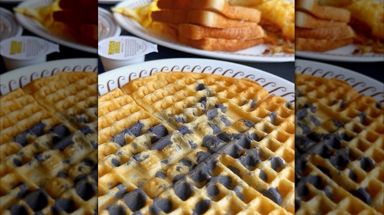 A Waffle House blueberry waffle in front of a plate of toast, hash browns, and eggs