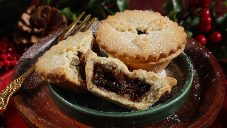 Two mincemeat pies with one cut in half to reveal the inside served by winter decor