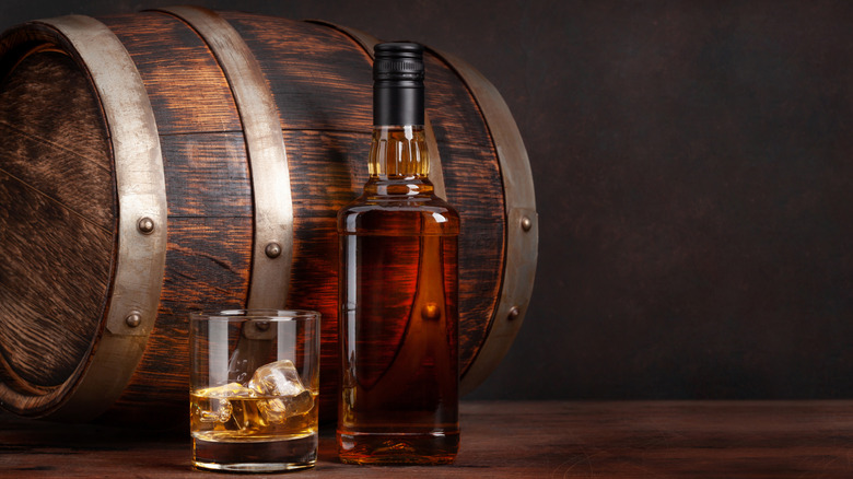 Aged whiskey in a barrel, bottle, and glass