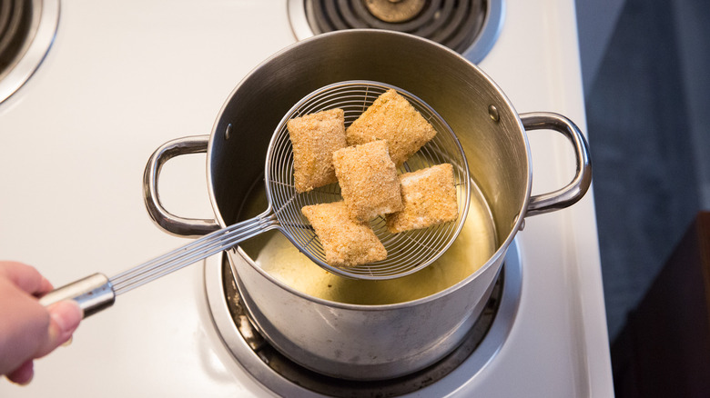 strainer lowering ravioli into oil