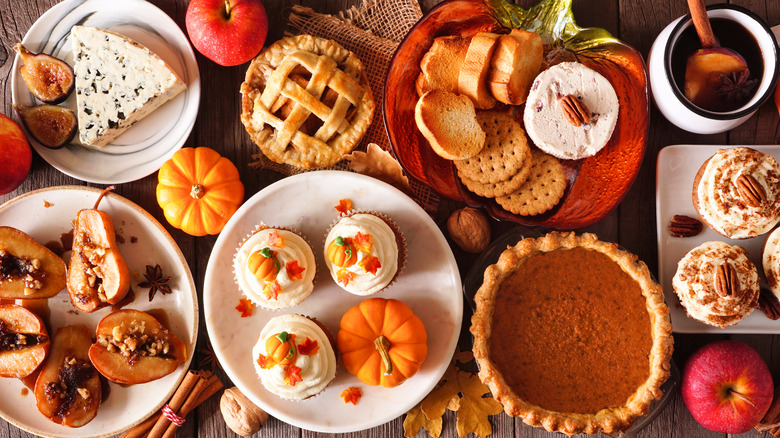 array of fall desserts, pumpkin pie, pumpkin cupcakes, baked pears, cheese and bread