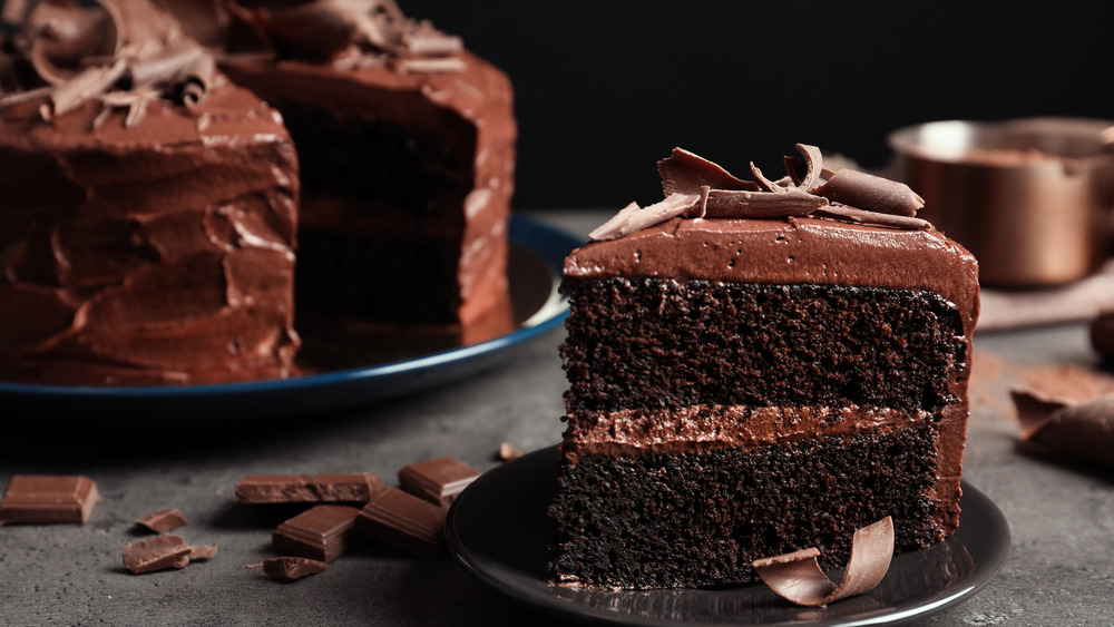 Whole chocolate cake with slice on plate